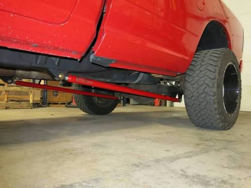 Red powder-coated custom trac bars under a lifted red truck