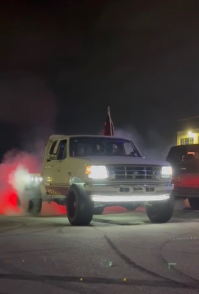 Lifted OBS Ford doing a burnout at night with lit LED bumper